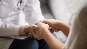 A health care provider and woman hold hands in a women's health center